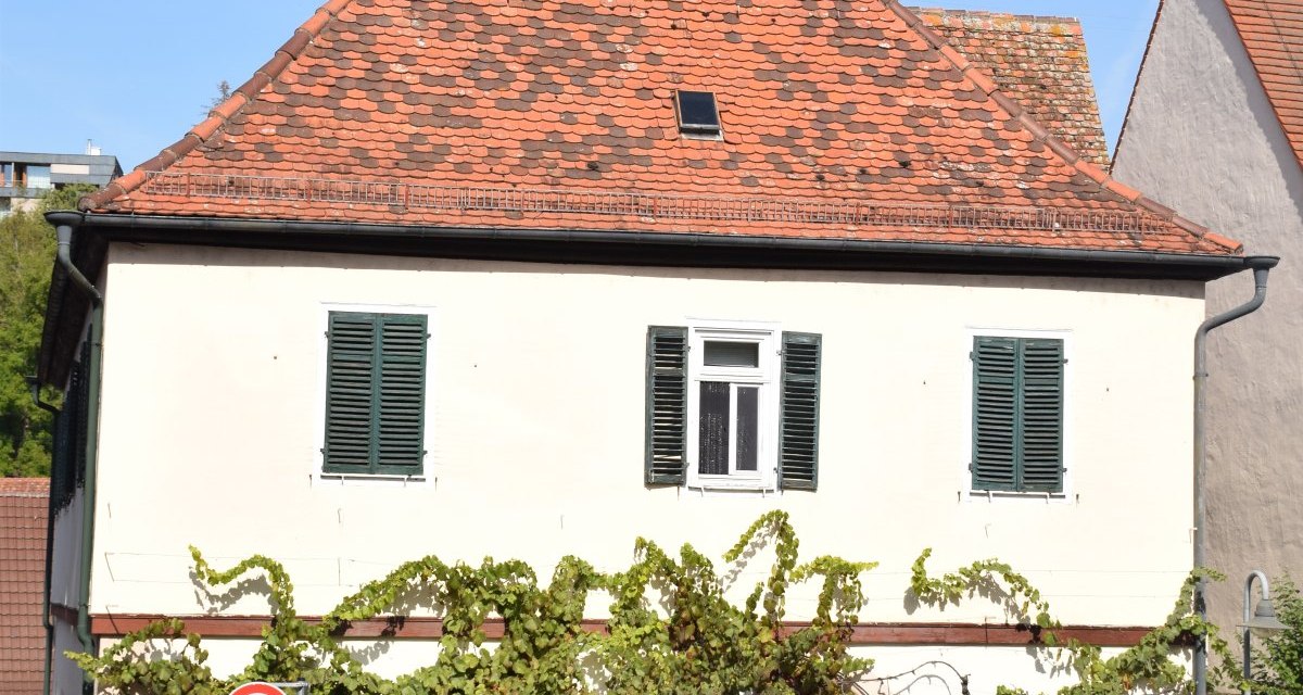 Zweigeschossiges Geb&auml;ude mit rotem Ziegeldach, gr&uuml;nen Fensterl&auml;den und Weinreben. Drei Autos parken davor, Verkehrsschild zeigt 30 km/h., &copy; Land der 1000 H&uuml;gel - Kraichgau-Stromberg