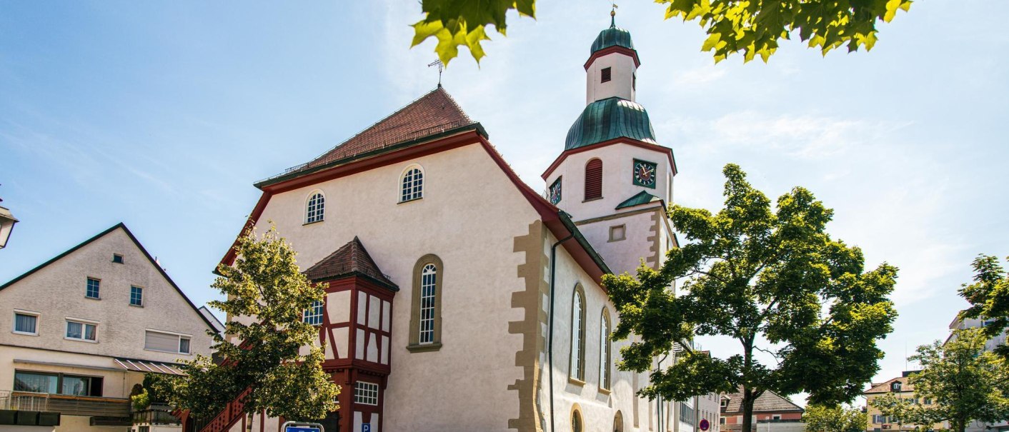 Eine Kirche in der Altstadt von Winnenden, umgeben von Bäumen und strahlendem Sonnenschein. Der Himmel ist klar und blau., © Stuttgart-Marketing GmbH, Sarah Schmid Eine Kirche in der Altstadt von Winnenden, umgeben von Bäumen und strahlendem Sonnenschein. Der Himmel ist klar und blau., © Stuttgart-Marketing GmbH, Sarah Schmid