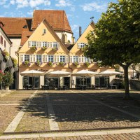 Marktplatz in Bietigheim-Bissingen mit historischen Gebäuden, Blumen und Sonnenschirmen vor einem Café. Ein Baum spendet Schatten., © Stuttgart Marketing GmbH, Sarah Schmid