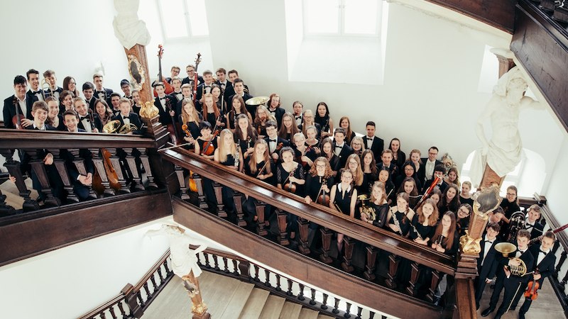 Das Landesjugendorchester Baden-W&uuml;rttemberg posiert auf einer Treppe. Die jungen Musiker halten ihre Instrumente und tragen formelle Kleidung., &copy; Sch&ouml;nblick gemeinn&uuml;tzige GmbH