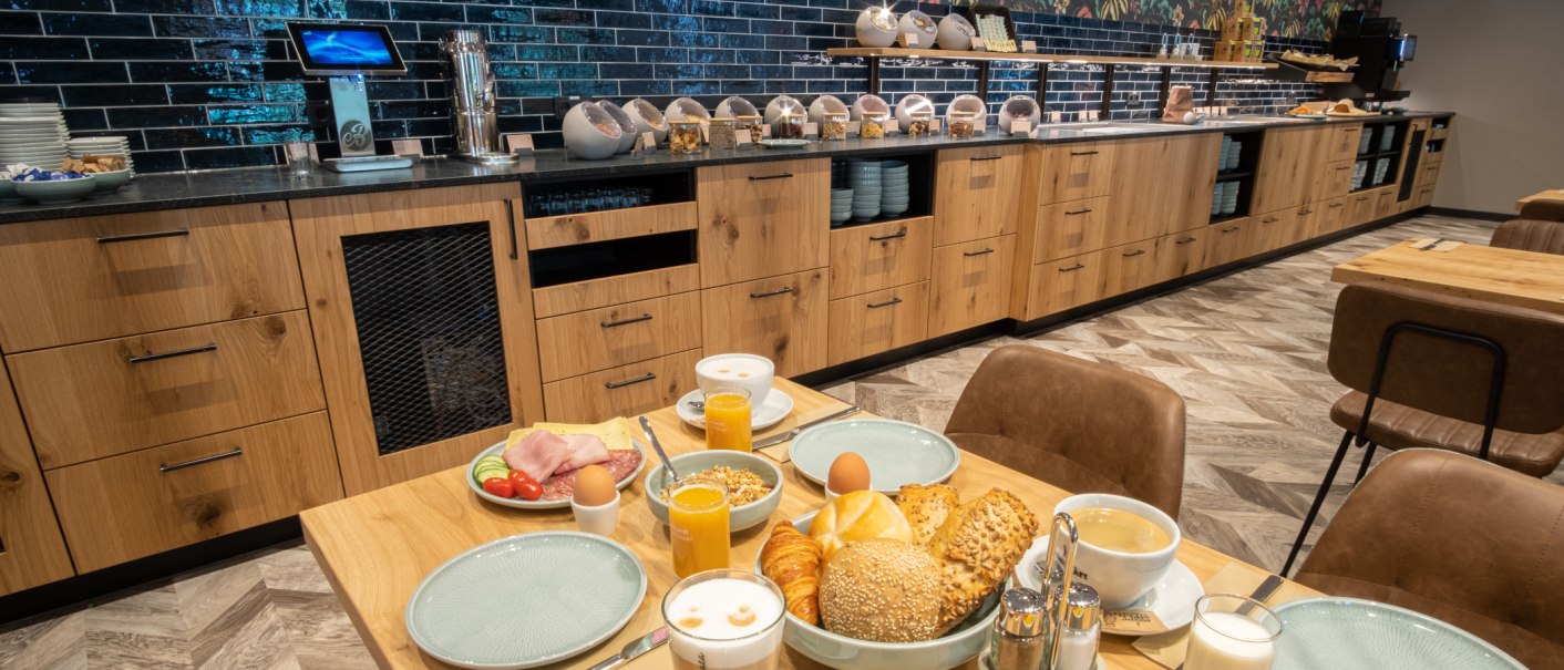 Ein reichhaltiges Frühstücksbuffet mit Brötchen, Croissants, Aufschnitt, Eiern und Getränken auf einem Tisch vor einer modernen Buffet-Theke., © 13 6 Design GmbH (Judenhof 10, 89073 Ulm) Ein reichhaltiges Frühstücksbuffet mit Brötchen, Croissants, Aufschnitt, Eiern und Getränken auf einem Tisch vor einer modernen Buffet-Theke., © 13 6 Design GmbH (Judenhof 10, 89073 Ulm)
