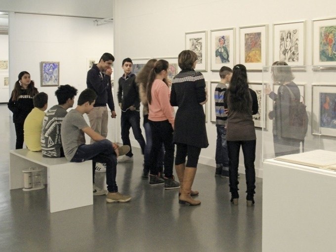 Jugendliche betrachten Kunstwerke in einer Galerie. Sie stehen und sitzen vor gerahmten Bildern an der Wand., &copy; Kunsthalle G&ouml;ppingen