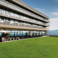 Modernes Hotel mit großen Fenstern, Terrasse mit Sonnenschirmen und grüner Wiese im Vordergrund, blauer Himmel im Hintergrund., © Achalm. Hotel GmbH & Co. KG Modernes Hotel mit großen Fenstern, Terrasse mit Sonnenschirmen und grüner Wiese im Vordergrund, blauer Himmel im Hintergrund., © Achalm. Hotel GmbH & Co. KG
