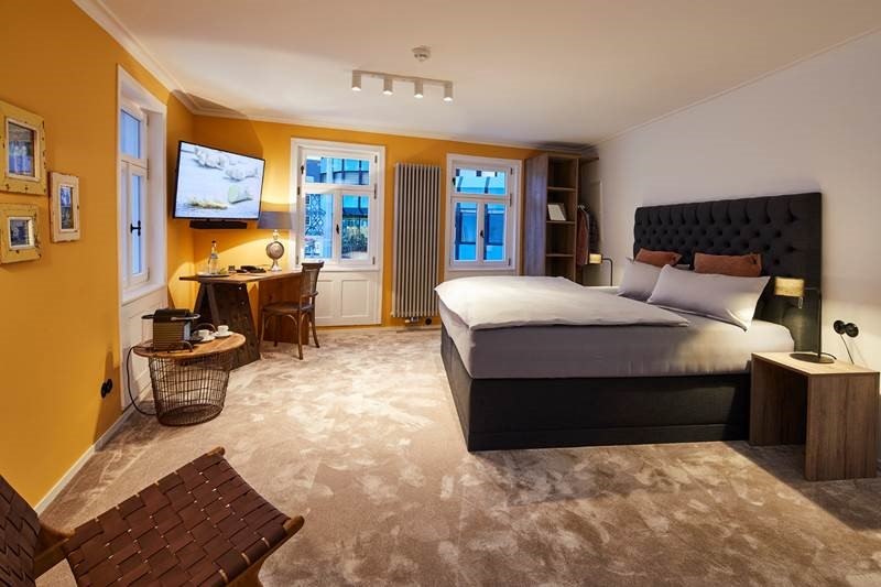 Modernes Schlafzimmer mit Doppelbett, Schreibtisch, Fernseher und warmen Farben. Große Fenster lassen viel Licht herein., © Hotel Restaurant Bachofer Modernes Schlafzimmer mit Doppelbett, Schreibtisch, Fernseher und warmen Farben. Große Fenster lassen viel Licht herein., © Hotel Restaurant Bachofer