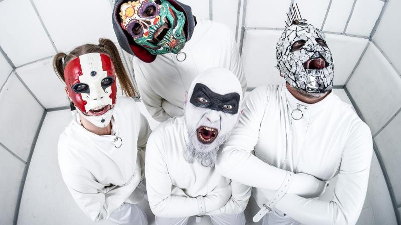 Vier Personen tragen wei&szlig;e Zwangsjacken und bunte Masken in einem wei&szlig;en, gepolsterten Raum. Sie schauen zur Kamera und haben die Arme verschr&auml;nkt., &copy; Music Circus Concertb&uuml;ro GmbH & Co. KG