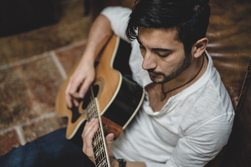 Ein Mann in einem wei&szlig;en Hemd spielt konzentriert auf einer Akustikgitarre. Die Szene wirkt entspannt und k&uuml;nstlerisch., &copy; Kulturstiftung Hohenlohe