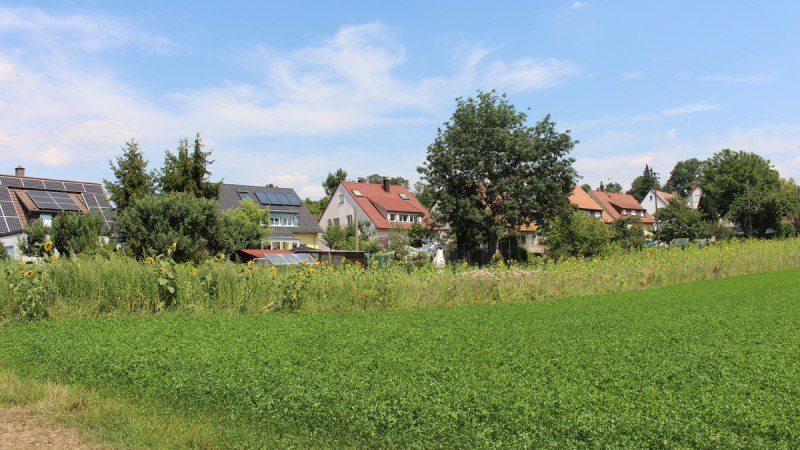 Häuser mit Solarpanelen am Ortsrand, umgeben von Bäumen und grünen Feldern unter blauem Himmel., © Ludwigsburg - Stuttgart-Marketing GmbH