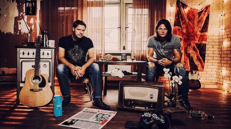 Zwei Männer sitzen in einem gemütlichen Raum mit Gitarre, Radio und britischer Flagge. Der Raum ist mit Lichterketten dekoriert., © Kulturfenster Bönnigheim e. V. Zwei Männer sitzen in einem gemütlichen Raum mit Gitarre, Radio und britischer Flagge. Der Raum ist mit Lichterketten dekoriert., © Kulturfenster Bönnigheim e. V.