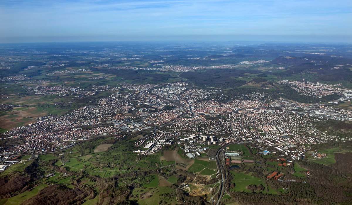 Luftaufnahme von Reutlingen, zeigt die Stadt mit dicht bebauten Gebieten, umgeben von grüner Landschaft und Feldern unter einem klaren Himmel., © Mythos Schwäbische Alb im Landkreis Reutlingen e.V.
