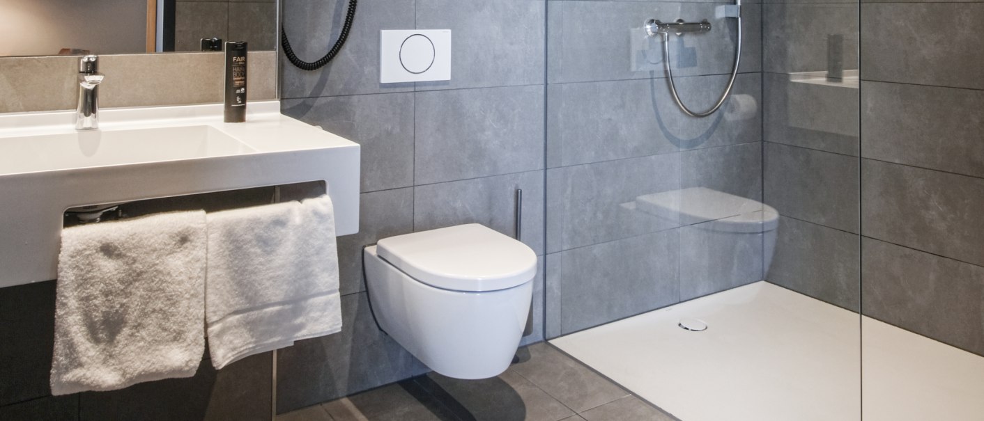 Modernes Badezimmer mit grauen Fliesen, Waschbecken, Handtuch, wandhängender Toilette und ebenerdiger Dusche., © 13 6 Design GmbH (Judenhof 10, 89073 Ulm) Modernes Badezimmer mit grauen Fliesen, Waschbecken, Handtuch, wandhängender Toilette und ebenerdiger Dusche., © 13 6 Design GmbH (Judenhof 10, 89073 Ulm)
