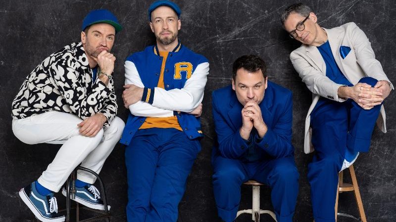 Vier Männer in blauen und weißen Outfits sitzen auf Hockern vor einem dunklen Hintergrund. Sie tragen sportliche Kleidung und schauen in die Kamera., © Backnang Vier Männer in blauen und weißen Outfits sitzen auf Hockern vor einem dunklen Hintergrund. Sie tragen sportliche Kleidung und schauen in die Kamera., © Backnang