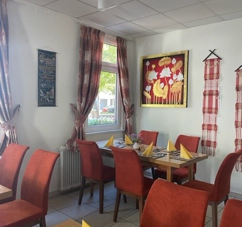 Ein gemütliches Restaurant mit roten Stühlen, gelben Servietten und asiatischer Dekoration an den Wänden., © cKabkao Ein gemütliches Restaurant mit roten Stühlen, gelben Servietten und asiatischer Dekoration an den Wänden., © cKabkao