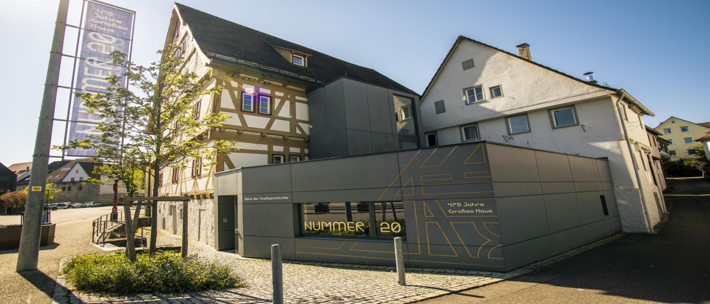 Modernes Gebäude mit Fachwerkhaus in Waiblingen, beschriftet als Haus der Stadtgeschichte. Ein Baum und ein Banner sind sichtbar., © SMG, Sarah Schmid