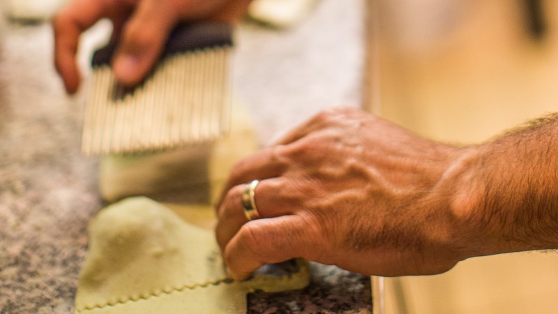 Hände schneiden frische Pasta mit einem Teigrädchen auf einer Arbeitsfläche., © La Signora Moro Hände schneiden frische Pasta mit einem Teigrädchen auf einer Arbeitsfläche., © La Signora Moro