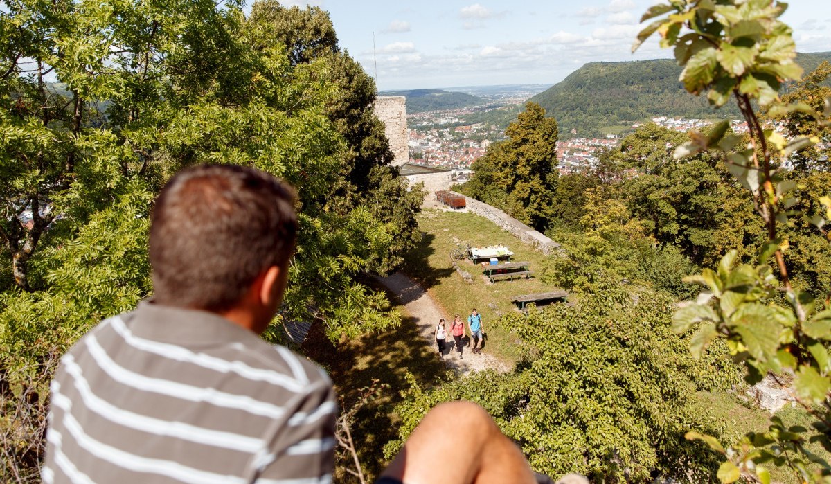 Person blickt von einem Hügel auf die Burgruine Helfenstein und Geislingen. Im Hintergrund sind Bäume und eine weite Landschaft zu sehen., © Landkreis Göppingen