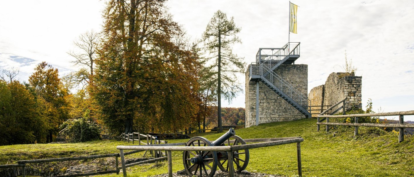 Burgruine Hiltenburg in Bad Ditzenbach mit Kanone im Vordergrund und herbstlichen Bäumen im Hintergrund., © SMG, Sarah Schmid Burgruine Hiltenburg in Bad Ditzenbach mit Kanone im Vordergrund und herbstlichen Bäumen im Hintergrund., © SMG, Sarah Schmid