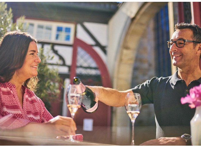 Ein Mann und eine Frau sitzen in einer Altstadt und genießen Sekt. Der Mann schenkt der Frau ein Glas ein. Im Hintergrund Fachwerkarchitektur., © Esslinger Stadtmarketing &amp; Tourismus GmbH