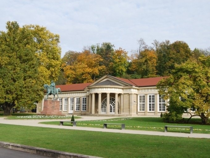 Historisches Gebäude im Kurpark Bad Cannstatt mit Reiterstatue und herbstlicher Baumkulisse., © Cool-Tours StattReisen