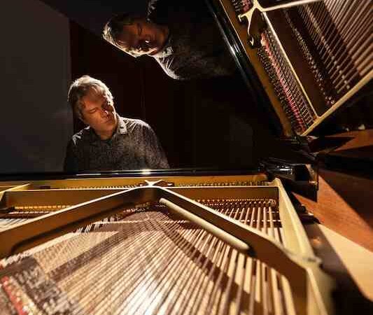 Ein Mann spielt konzentriert Klavier, das Innere des Fl&uuml;gels ist im Vordergrund zu sehen. Der Raum ist dunkel, der Fokus liegt auf dem Musiker., &copy; Kulturhaus Schwanen