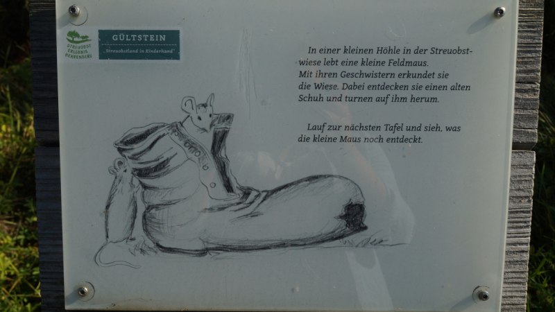 Infotafel mit einer Zeichnung einer Maus in einem Schuh. Der Text beschreibt das Leben einer Feldmaus auf einer Streuobstwiese., &copy; Natur.Nah. Sch&ouml;nbuch & Heckeng&auml;u