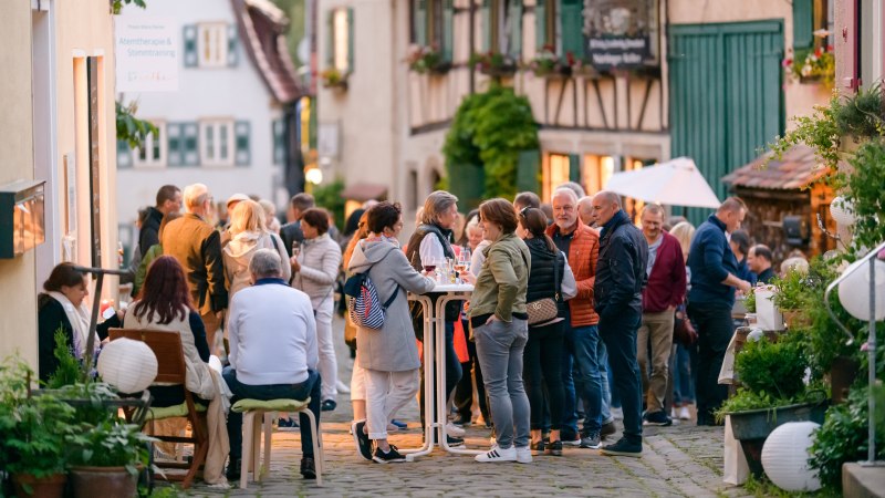 Menschen versammeln sich in einer malerischen Altstadtgasse, um bei einem Event zu essen und zu trinken. Die Atmosphäre ist lebhaft und gesellig., © Citymarketing Menschen versammeln sich in einer malerischen Altstadtgasse, um bei einem Event zu essen und zu trinken. Die Atmosphäre ist lebhaft und gesellig., © Citymarketing