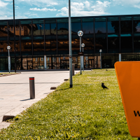 Der Landtag von Baden-W&uuml;rttemberg mit moderner Glasfassade und einem gelben Schild im Vordergrund. Im Hintergrund ist der Fernsehturm zu sehen., &copy; Stuttgart-Marketing GmbH, Sarah Schmid
