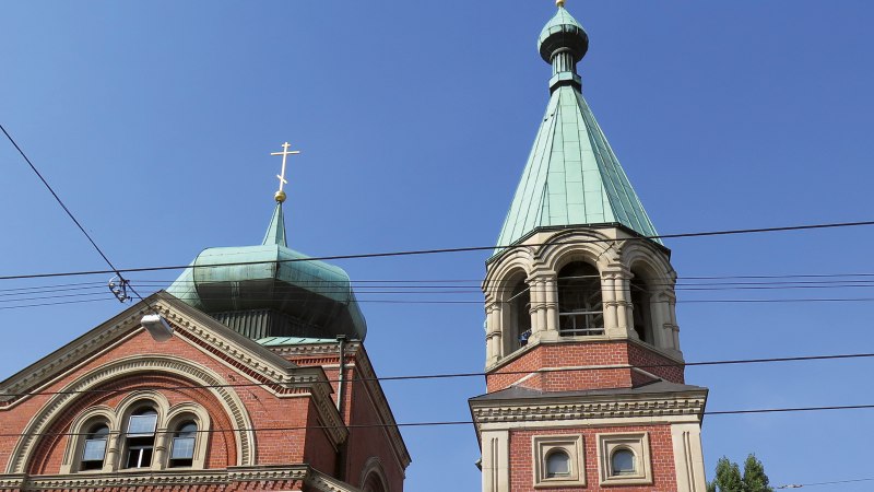 Zwei Kirchtürme der russischen Kirche St. Nikolai mit blauen Dächern und goldenen Kreuzen vor klarem Himmel., © SMG Zwei Kirchtürme der russischen Kirche St. Nikolai mit blauen Dächern und goldenen Kreuzen vor klarem Himmel., © SMG