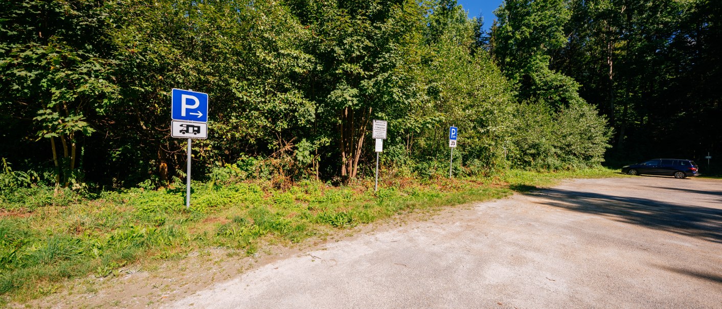 Ein Parkplatz am Waldrand mit Schildern f&uuml;r Wohnmobilstellpl&auml;tze. Ein Auto steht am rechten Rand. Der Himmel ist klar und blau., &copy; Stuttgart-Marketing GmbH, Thomas Niederm&uuml;ller