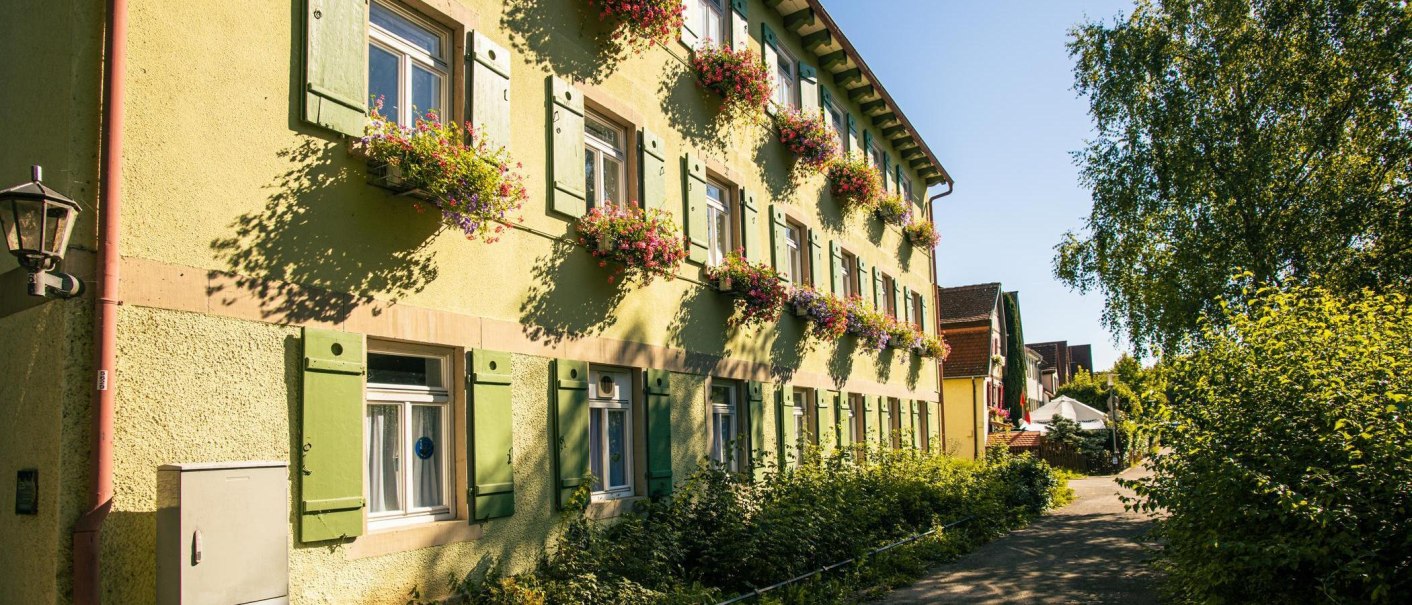 Ein gelbes Haus mit grünen Fensterläden und Blumenkästen in einer sonnigen Straße in Bietigheim-Bissingen., © Stuttgart-Marketing GmbH, Sarah Schmid