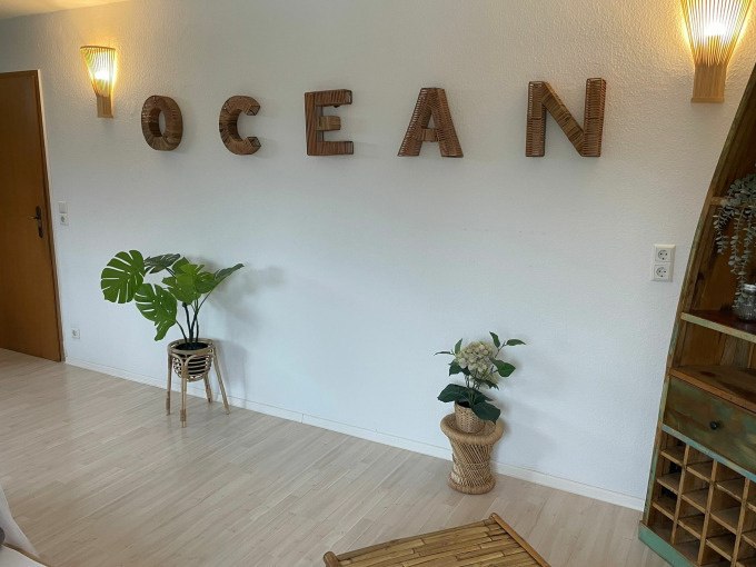 Heller Raum mit Holzboden, Pflanzen in Körben und dem Wort 'OCEAN' aus Holzbuchstaben an der Wand., © Cool-Tours StattReisen Heller Raum mit Holzboden, Pflanzen in Körben und dem Wort 'OCEAN' aus Holzbuchstaben an der Wand., © Cool-Tours StattReisen