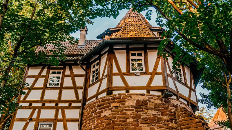 Fachwerkhaus mit rundem Turm, umgeben von B&auml;umen. Der Turm hat ein spitzes Dach, das Geb&auml;ude ist aus Holz und Stein gebaut., &copy; Stuttgart-Marketing GmbH, Thomas Niederm&uuml;ller