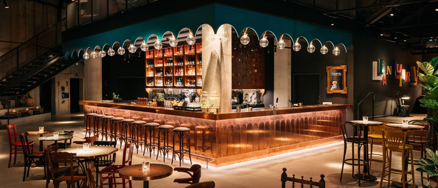 Stilvolle Bar mit Kupfertheke, hängenden Glaskugelleuchten und gemütlichen Sitzbereichen. Moderne Einrichtung mit warmem Licht und dekorativen Elementen., © © Ruby Hotels Stilvolle Bar mit Kupfertheke, hängenden Glaskugelleuchten und gemütlichen Sitzbereichen. Moderne Einrichtung mit warmem Licht und dekorativen Elementen., © © Ruby Hotels