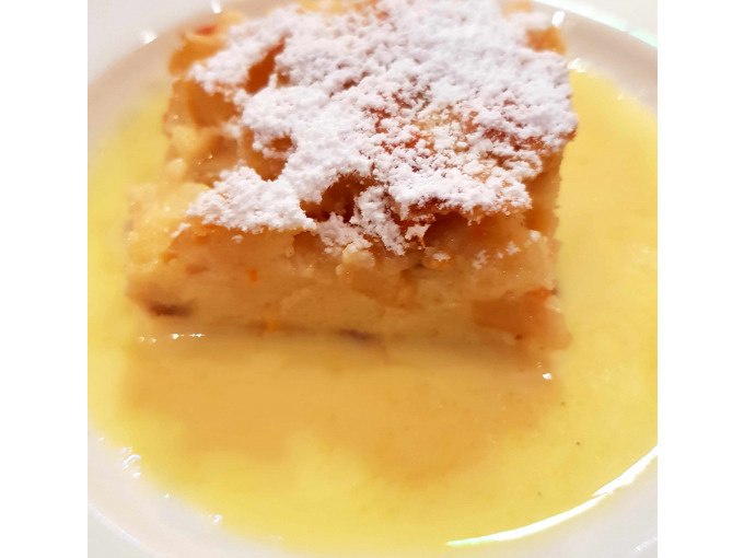 Ein St&uuml;ck Kuchen mit Puderzucker bestreut, serviert auf einem Teller mit Vanilleso&szlig;e., &copy; Kultweine-Kochwelten-Kunst&uuml;cke - Kochschule Sonja Lenz