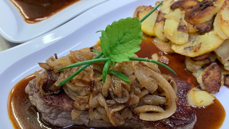 Zwei Teller mit Zwiebelrostbraten und knusprigen Bratkartoffeln, garniert mit frischen Kr&auml;utern. Ein traditionelles schw&auml;bisches Gericht., &copy; Schw&auml;bischesGasthaus