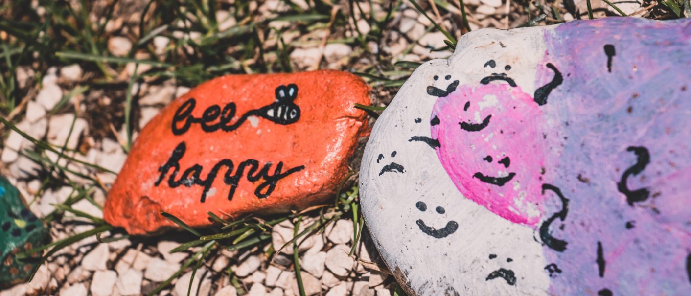 Zwei bemalte Steine liegen auf Gras. Einer ist orange mit der Aufschrift 'bee happy', der andere hat ein rosa Herz und schwarze Muster., © Stadt Welzheim
