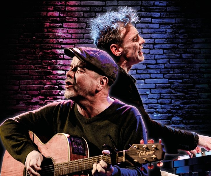 Zwei Musiker performen leidenschaftlich auf einer Bühne, einer mit Gitarre, der andere am Keyboard, vor einer beleuchteten Backsteinwand., © Kulturhaus Schwanen Zwei Musiker performen leidenschaftlich auf einer Bühne, einer mit Gitarre, der andere am Keyboard, vor einer beleuchteten Backsteinwand., © Kulturhaus Schwanen