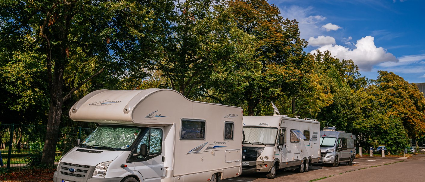 Wohnmobile parken auf einem Stellplatz in Ludwigsburg, umgeben von grünen Bäumen und blauem Himmel., © Stuttgart-Marketing GmbH, Thomas Niedermüller
