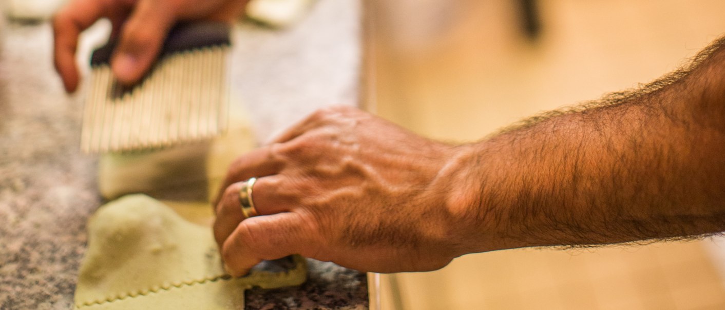 Hände schneiden frische Pasta mit einem Teigrädchen auf einer Arbeitsfläche., © La Signora Moro Hände schneiden frische Pasta mit einem Teigrädchen auf einer Arbeitsfläche., © La Signora Moro