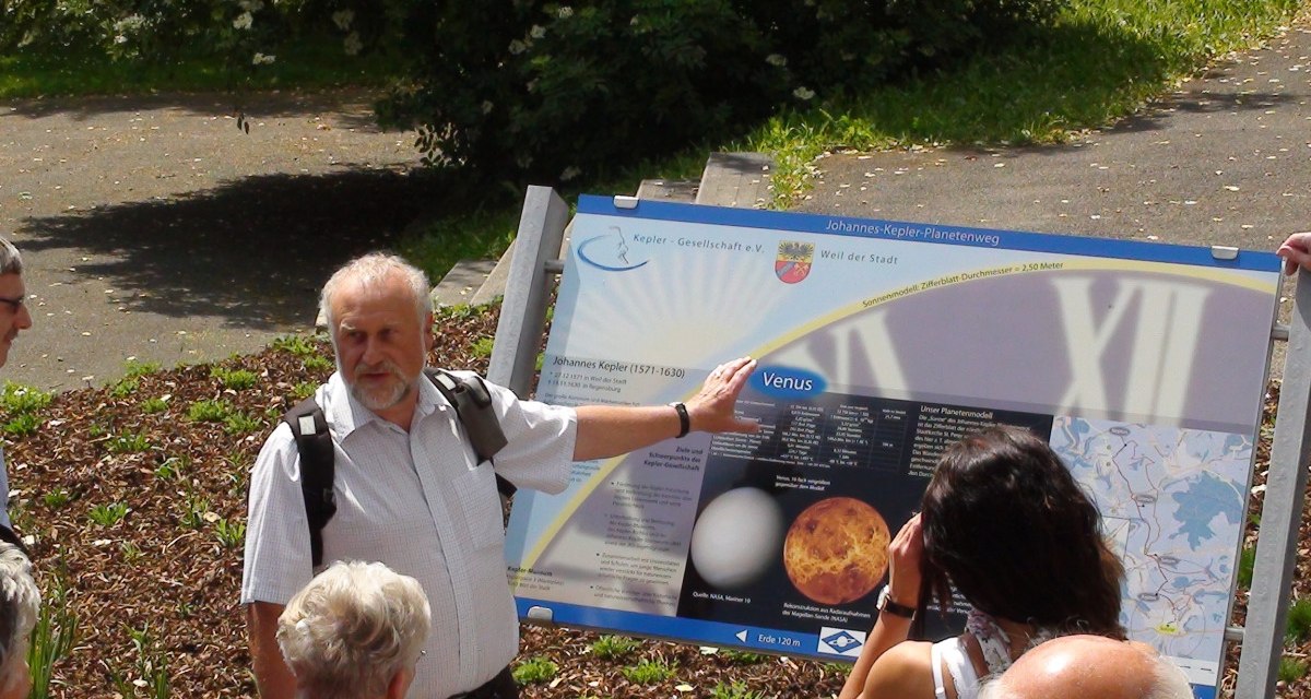 Ein Mann zeigt einer Gruppe eine Tafel über die Venus auf dem Johannes-Kepler-Planetenweg. Die Tafel enthält Bilder und Informationen., © Natur.Nah. Schönbuch & Heckengäu Ein Mann zeigt einer Gruppe eine Tafel über die Venus auf dem Johannes-Kepler-Planetenweg. Die Tafel enthält Bilder und Informationen., © Natur.Nah. Schönbuch & Heckengäu