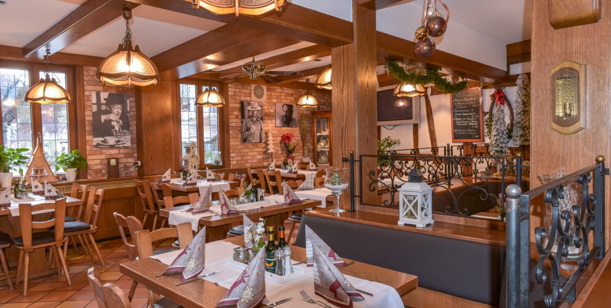 Gemütliches Restaurant mit Holzmöbeln, gedeckten Tischen und weihnachtlicher Dekoration. An den Wänden hängen Bilder, die Beleuchtung ist warm. Gemütliches Restaurant mit Holzmöbeln, gedeckten Tischen und weihnachtlicher Dekoration. An den Wänden hängen Bilder, die Beleuchtung ist warm.