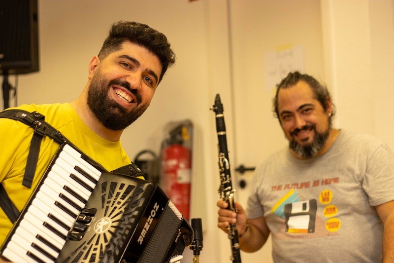 Zwei Musiker l&auml;cheln in die Kamera. Der eine spielt Akkordeon, der andere Klarinette. Sie wirken fr&ouml;hlich und entspannt., &copy; Kulturhaus Schwanen