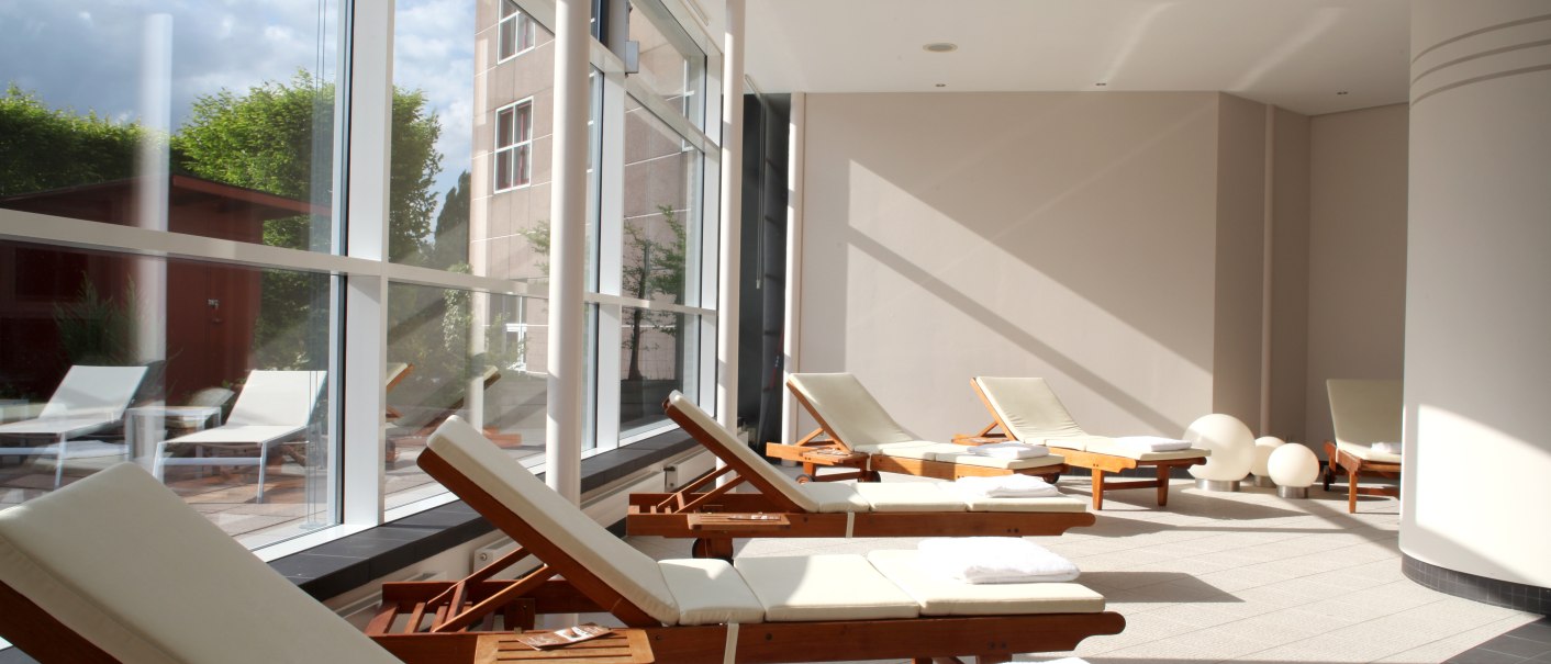 Heller Wellnessbereich mit Liegestühlen und großen Fenstern, die viel Tageslicht hereinlassen. Handtücher liegen auf den Stühlen bereit., © Pullman Stuttgart Fontana Heller Wellnessbereich mit Liegestühlen und großen Fenstern, die viel Tageslicht hereinlassen. Handtücher liegen auf den Stühlen bereit., © Pullman Stuttgart Fontana