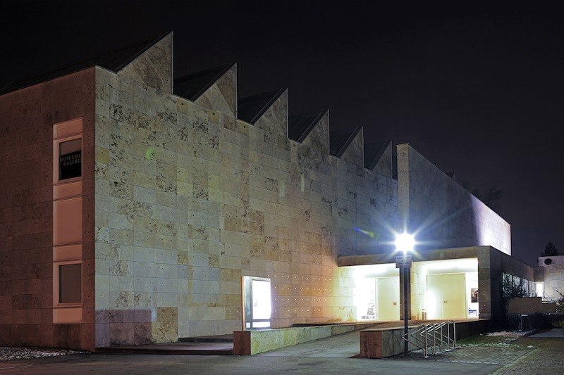 Eine moderne Galerie bei Nacht, beleuchtet mit einem hellen Eingang. Die Architektur ist schlicht und geometrisch., © Stadt Kornwestheim Kulturmanagement Eine moderne Galerie bei Nacht, beleuchtet mit einem hellen Eingang. Die Architektur ist schlicht und geometrisch., © Stadt Kornwestheim Kulturmanagement