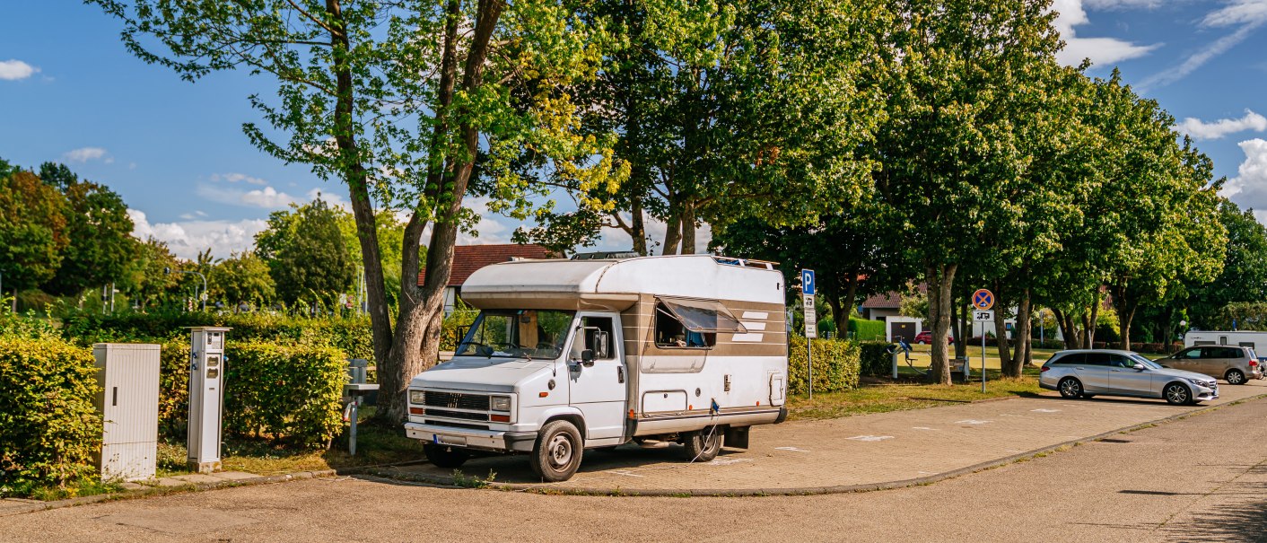 Ein Wohnmobil steht auf einem Stellplatz in Marbach am Neckar, umgeben von Bäumen und geparkten Autos. Der Himmel ist blau mit einigen Wolken., © Stuttgart-Marketing GmbH, Thomas Niedermüller