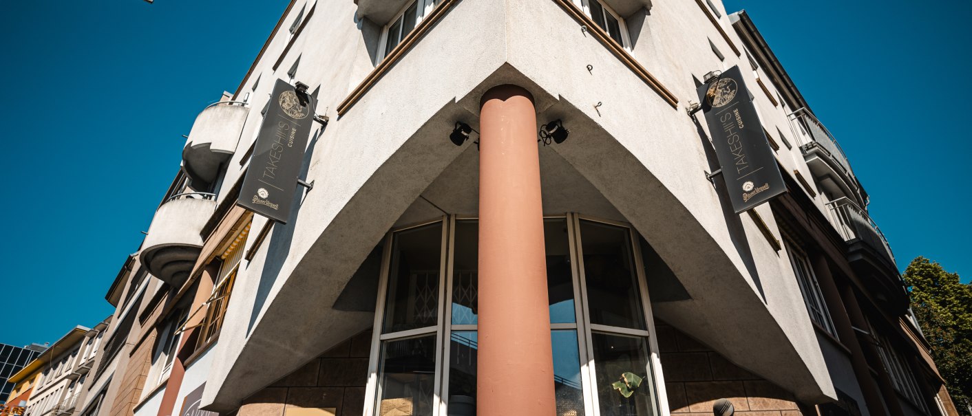 Eckgebäude mit Schildern von Takeshiis Lounge und Vivi Beauty Nails, aufgenommen von unten. Straßenschild Wagnerstraße sichtbar, blauer Himmel im Hintergrund., © SMG Stuttgart Marketing GmbH - Sarah Schmid