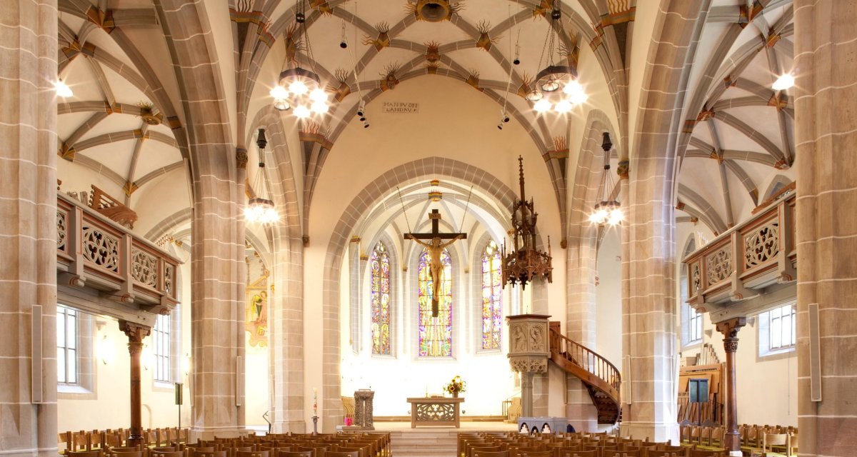 Innenansicht der Michaelskirche mit gotischen Bögen, Buntglasfenstern und Holzbänken. Der Altarbereich ist zentral im Bild., © Remstal Tourismus e.V. Innenansicht der Michaelskirche mit gotischen Bögen, Buntglasfenstern und Holzbänken. Der Altarbereich ist zentral im Bild., © Remstal Tourismus e.V.