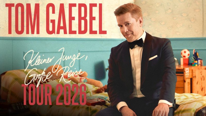 Ein Mann im Anzug sitzt auf einem Bett in einem Kinderzimmer. Text: Tom Gaebel - Kleiner Junge, große Reise - Tour 2026., © TomGaebel Ein Mann im Anzug sitzt auf einem Bett in einem Kinderzimmer. Text: Tom Gaebel - Kleiner Junge, große Reise - Tour 2026., © TomGaebel