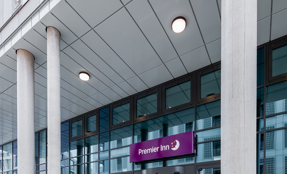 Eingang eines Premier Inn Hotels mit moderner Glasfassade und großen Säulen. Das Logo ist über der Tür sichtbar., © Premier Inn