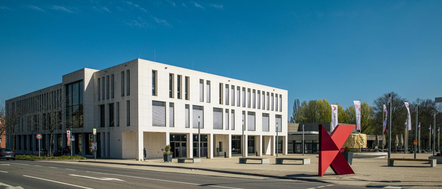 Modernes Gebäude in Kornwestheim mit großen Fenstern und einem roten K-Symbol im Vordergrund. Klare Linien und blauer Himmel im Hintergrund., © SMG, Sarah Schmid Modernes Gebäude in Kornwestheim mit großen Fenstern und einem roten K-Symbol im Vordergrund. Klare Linien und blauer Himmel im Hintergrund., © SMG, Sarah Schmid