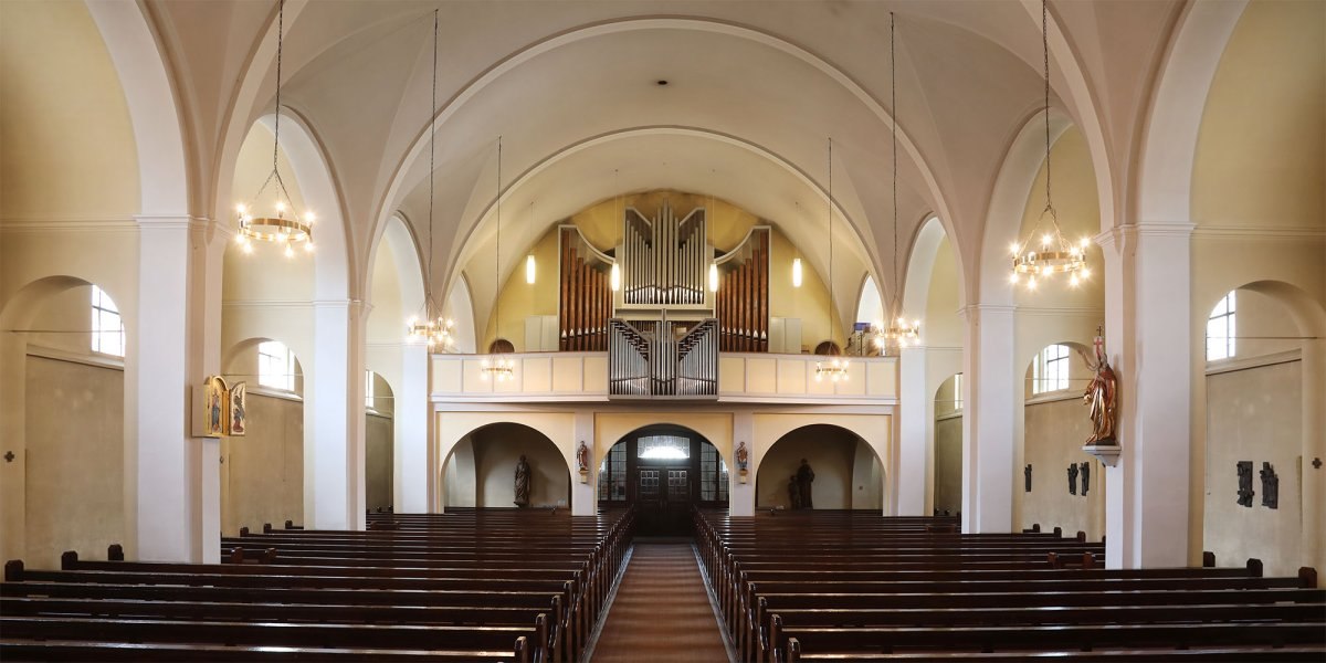 Innenansicht der Kirche St. Bernhard mit hohen Gewölben, einer großen Orgel und Holzbänken. An den Wänden sind Statuen und Leuchter zu sehen., © Katholisches Pfarramt Heubach Innenansicht der Kirche St. Bernhard mit hohen Gewölben, einer großen Orgel und Holzbänken. An den Wänden sind Statuen und Leuchter zu sehen., © Katholisches Pfarramt Heubach